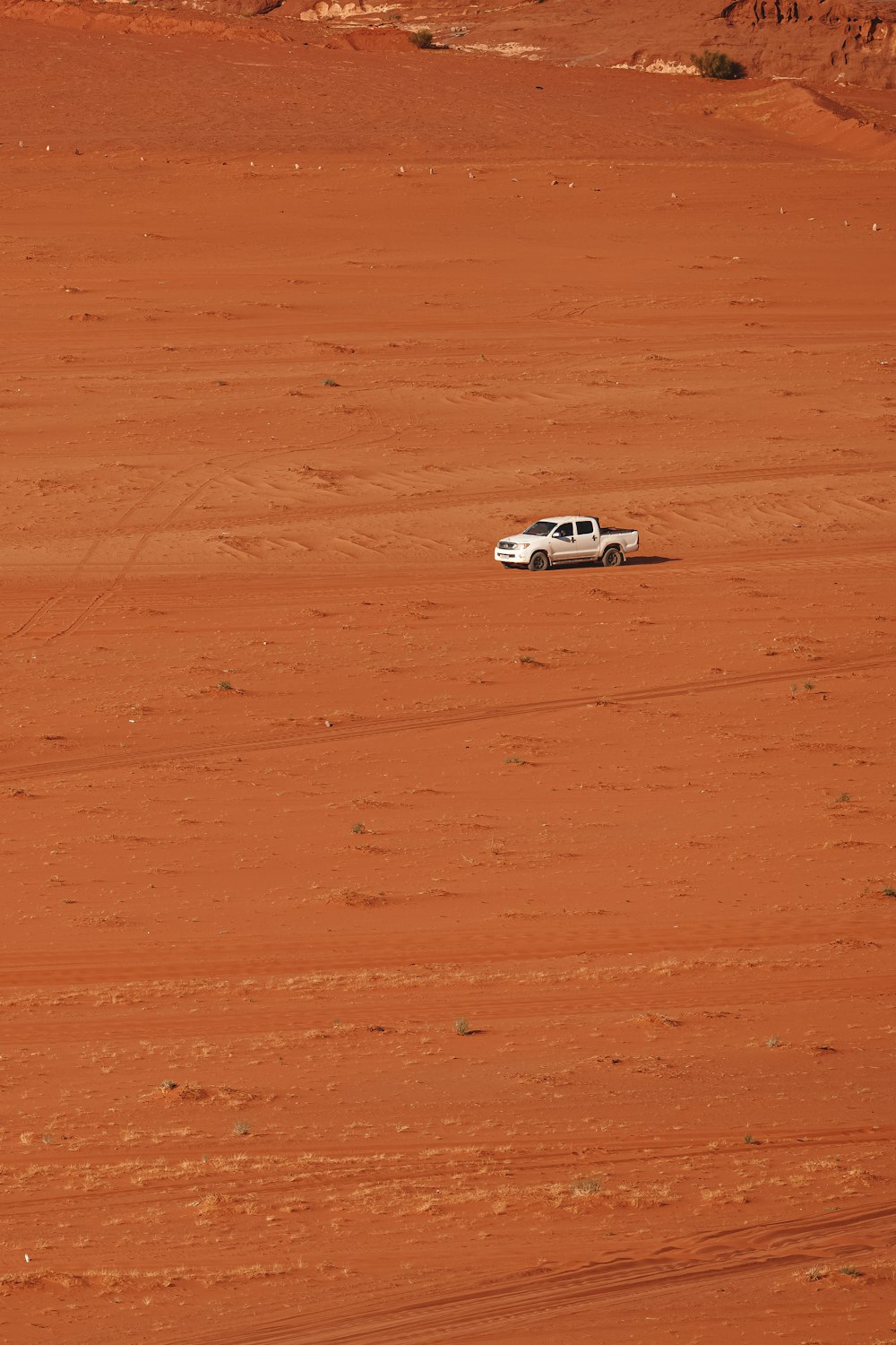 a white truck driving across a dirt field