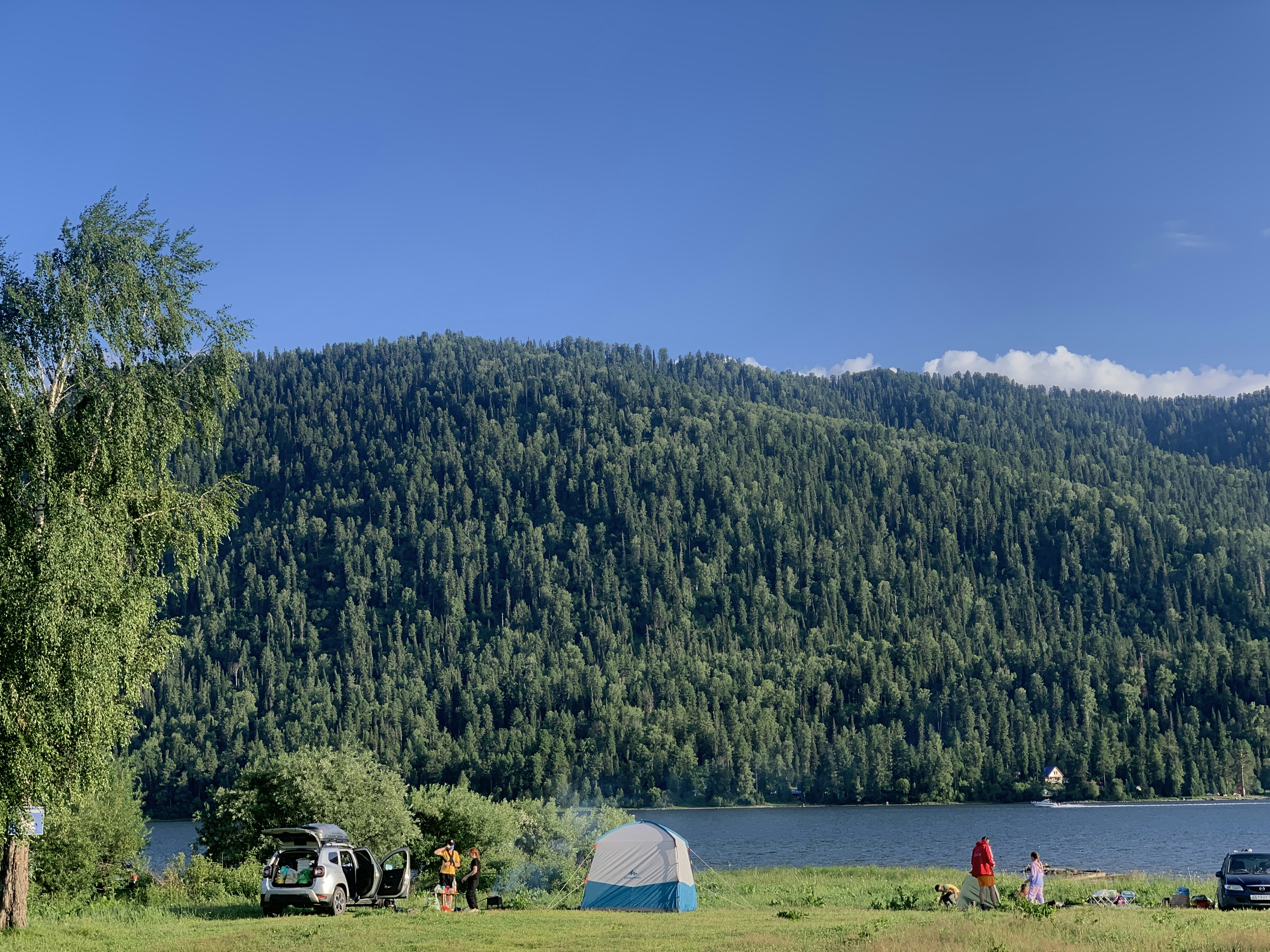 a group of people camping in a field next to a lake