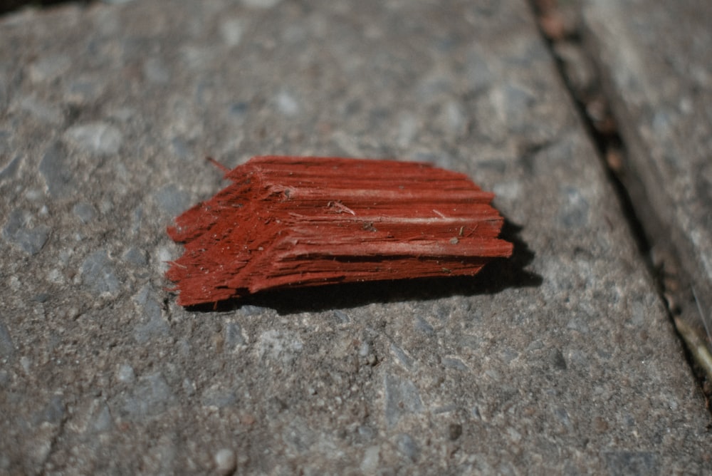 Un pedazo de madera rojo sentado encima de una acera