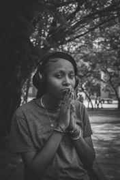 a woman wearing headphones and praying in a park