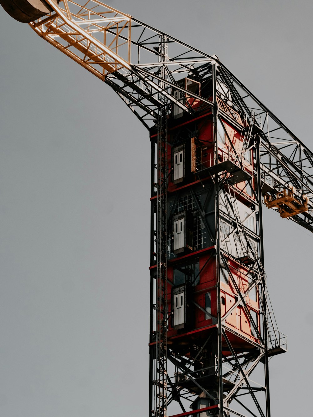 a red and white tower crane with a clock on it's side