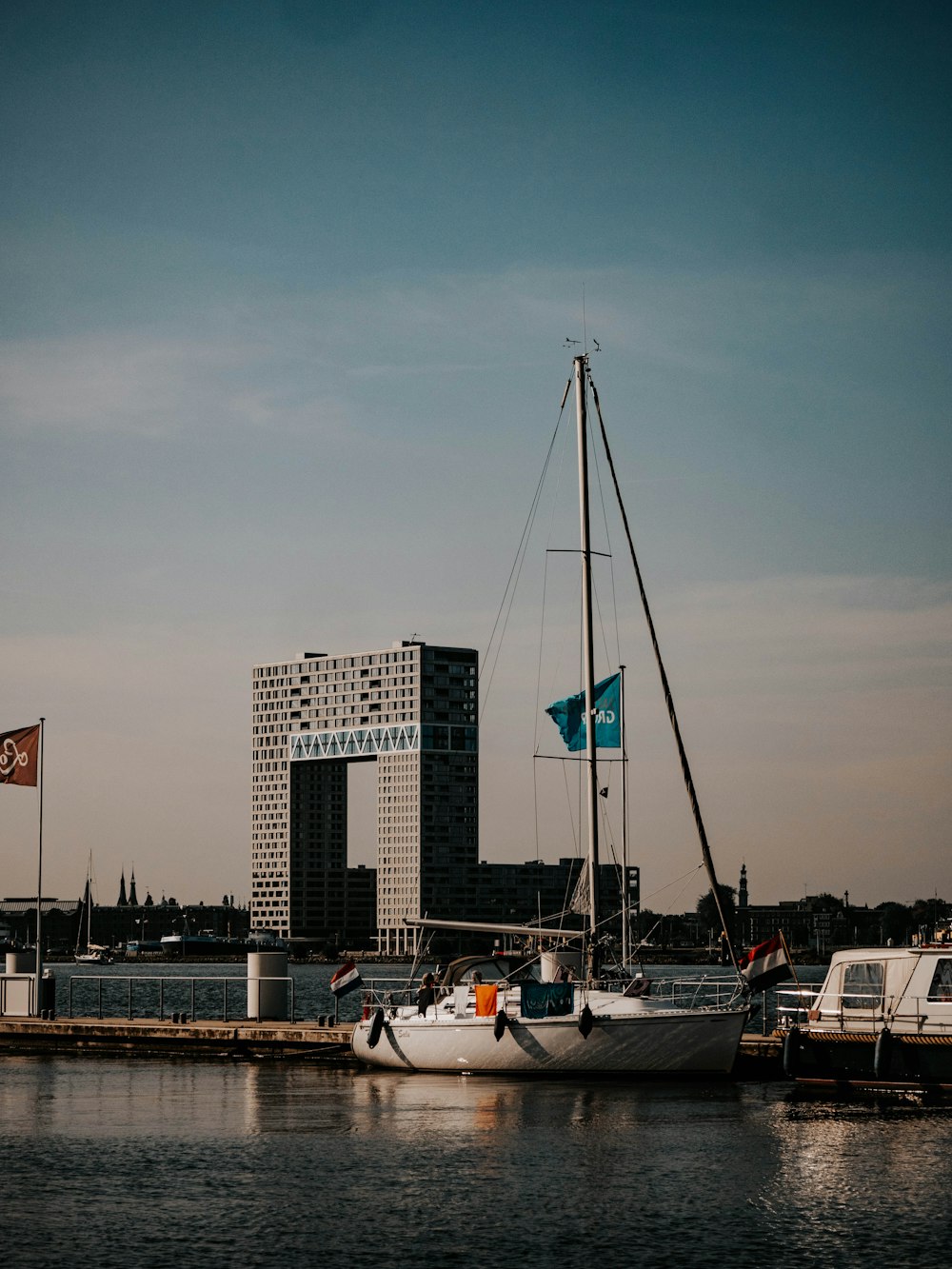 a sailboat docked in a harbor with a city in the background