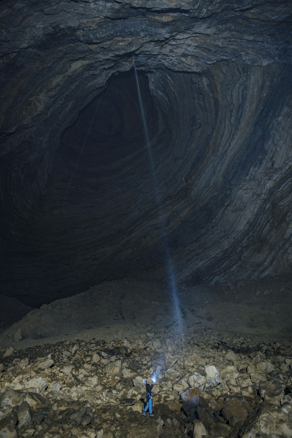 a person standing in a cave with a flashlight