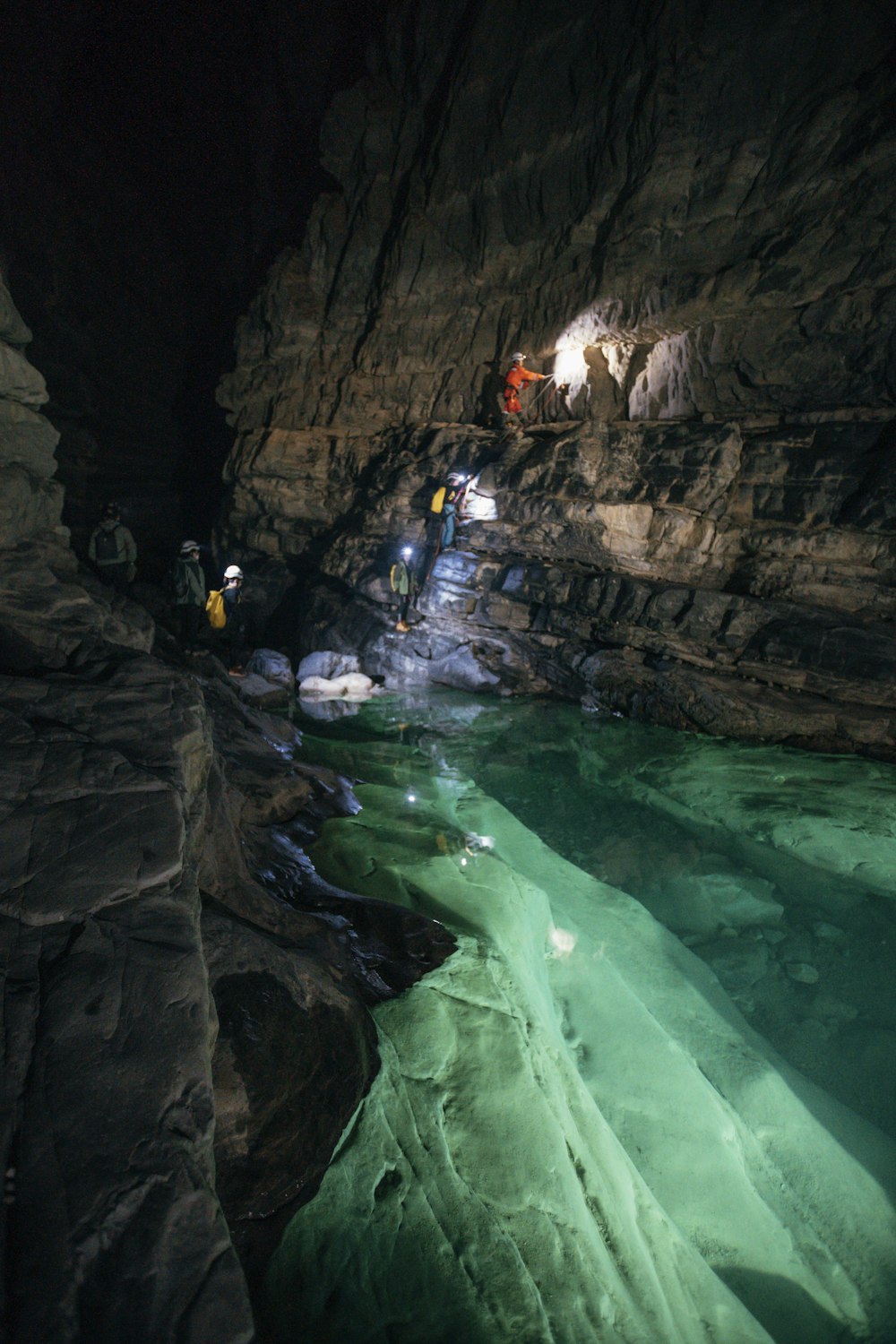 a group of people standing in a cave next to a body of water