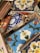 A variety of colorful ceramic tiles with intricate floral and geometric patterns. The tiles are stacked haphazardly, showcasing designs in blue, red, yellow, and white with bold outlines. Each tile features distinct artistic motifs that reflect a blend of traditional and modern styles.