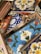 A variety of colorful ceramic tiles with intricate floral and geometric patterns. The tiles are stacked haphazardly, showcasing designs in blue, red, yellow, and white with bold outlines. Each tile features distinct artistic motifs that reflect a blend of traditional and modern styles.