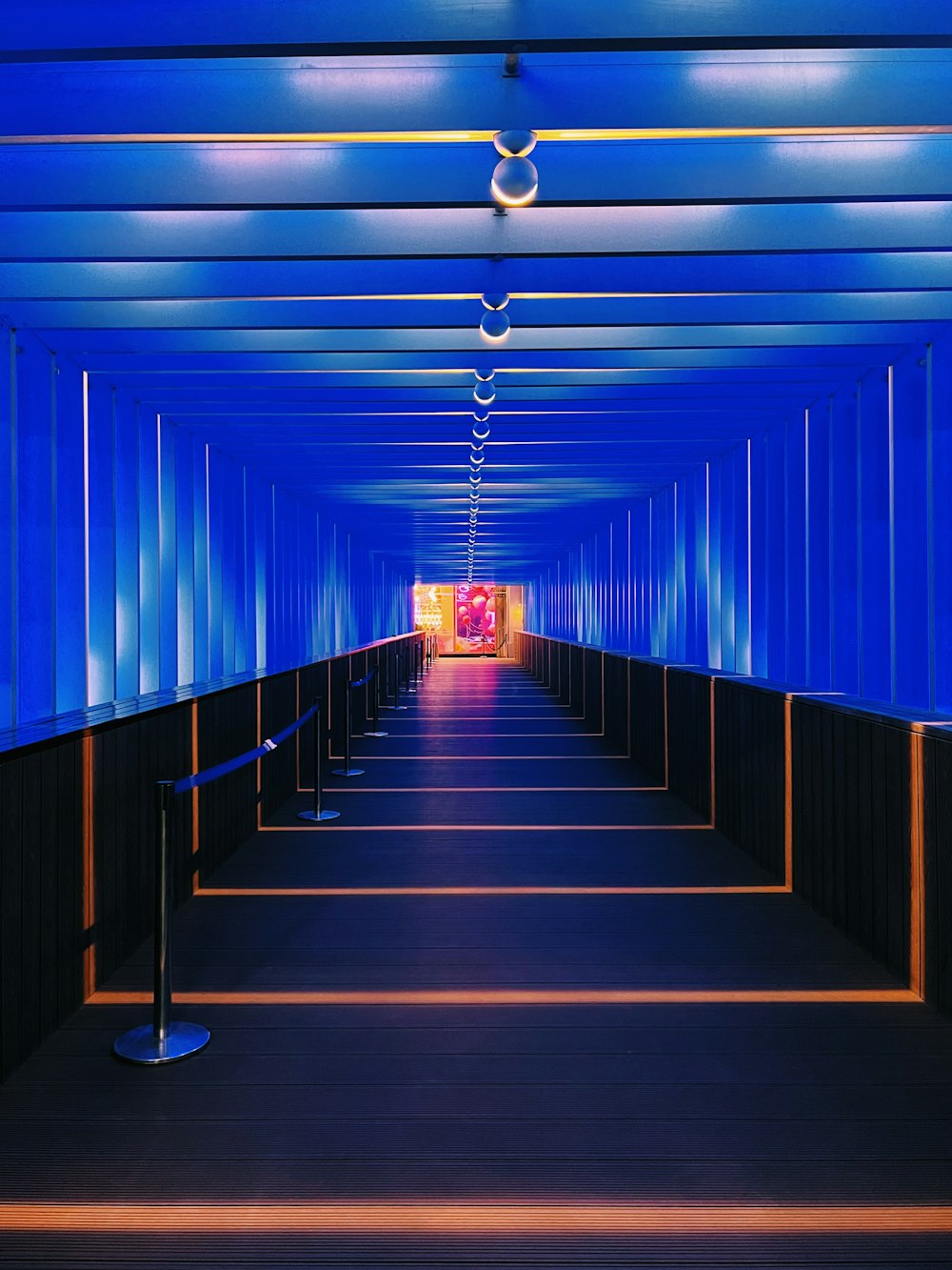 a long hallway with blue walls and a light at the end