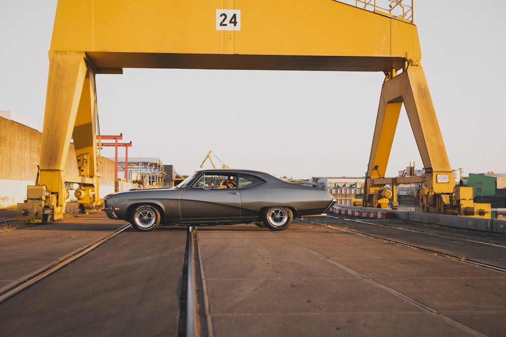 a car is parked under a yellow bridge