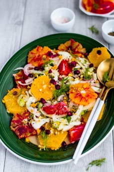 a green plate topped with a salad covered in fruit