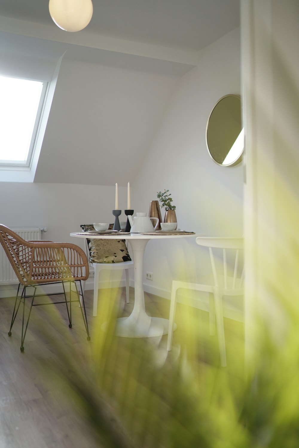 a room with a table, chairs and a round mirror