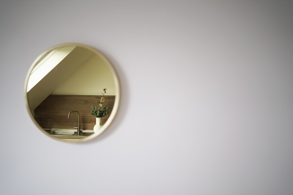 a round mirror hanging on a wall above a sink