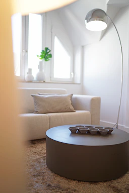 A modern minimalistic interior living room with warm lighting highlighting a sleek dark sofa and golden accents.