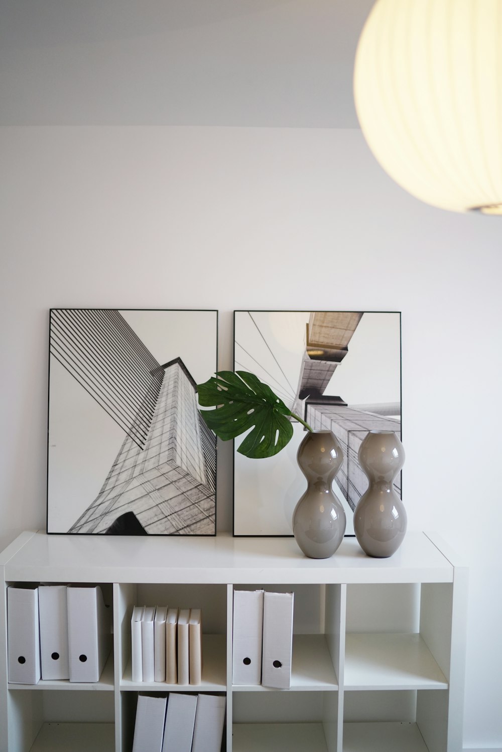 a white shelf with two vases and a mirror