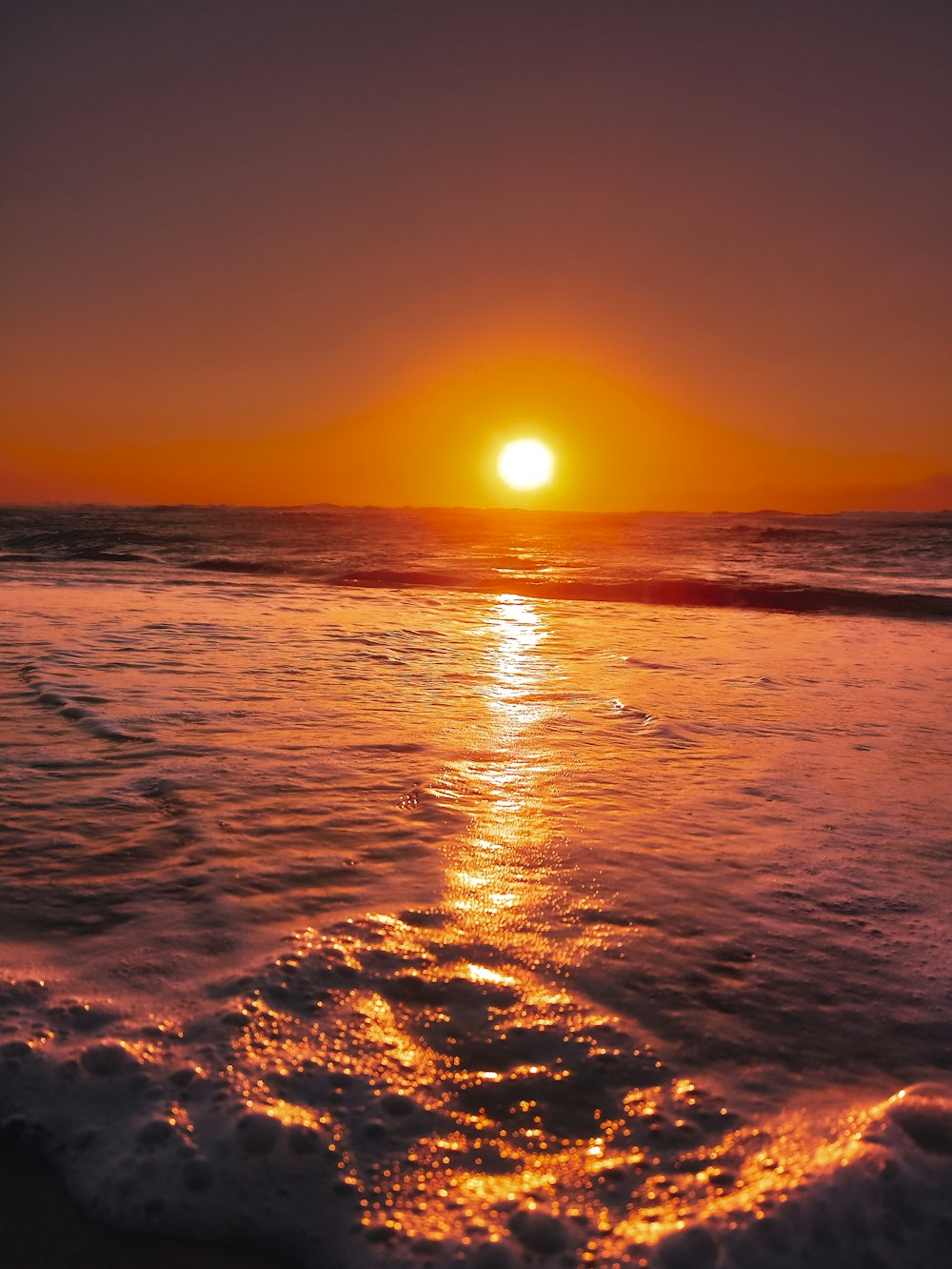 the sun is setting over the water at the beach