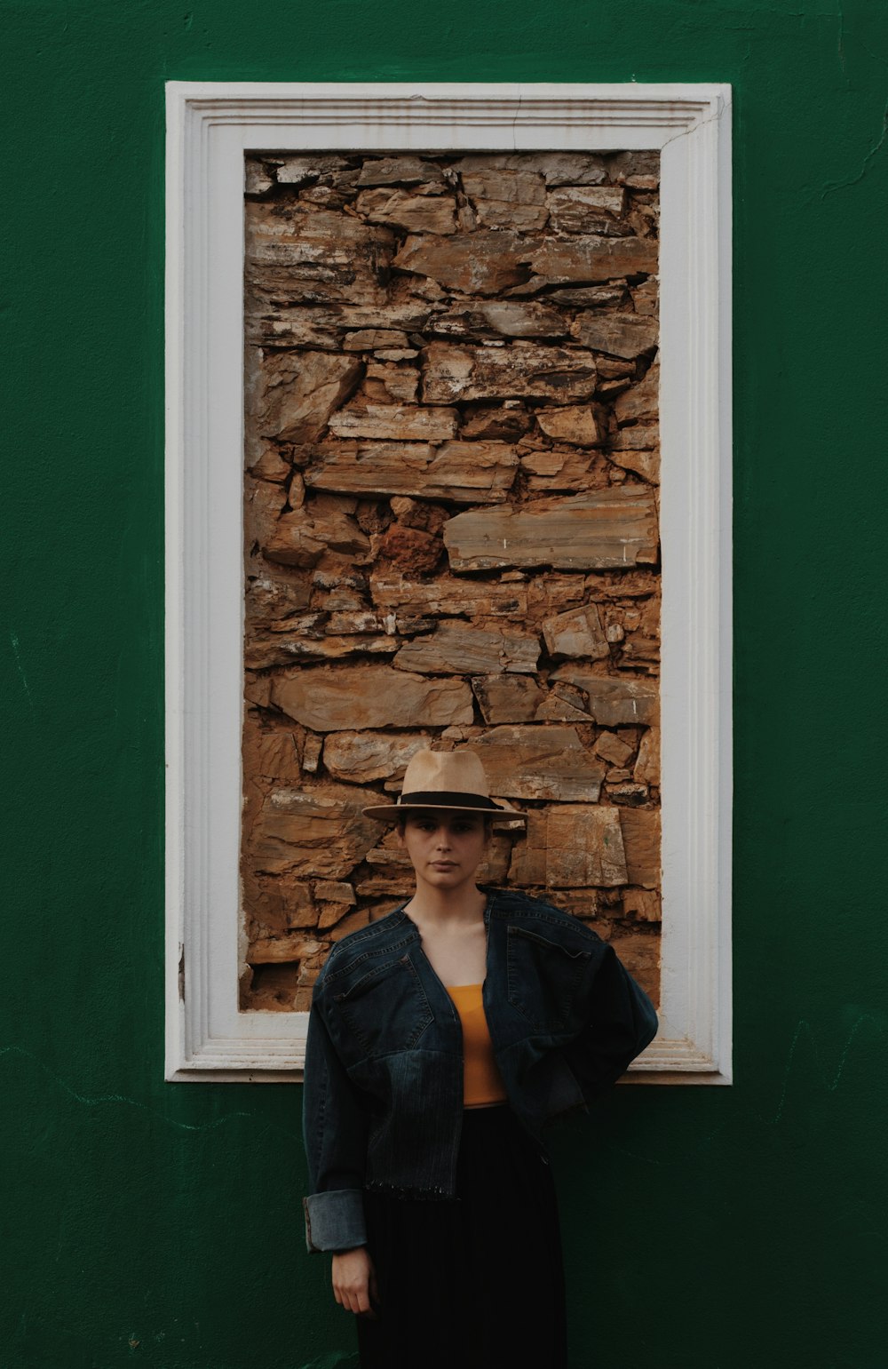 a woman standing in front of a stone wall