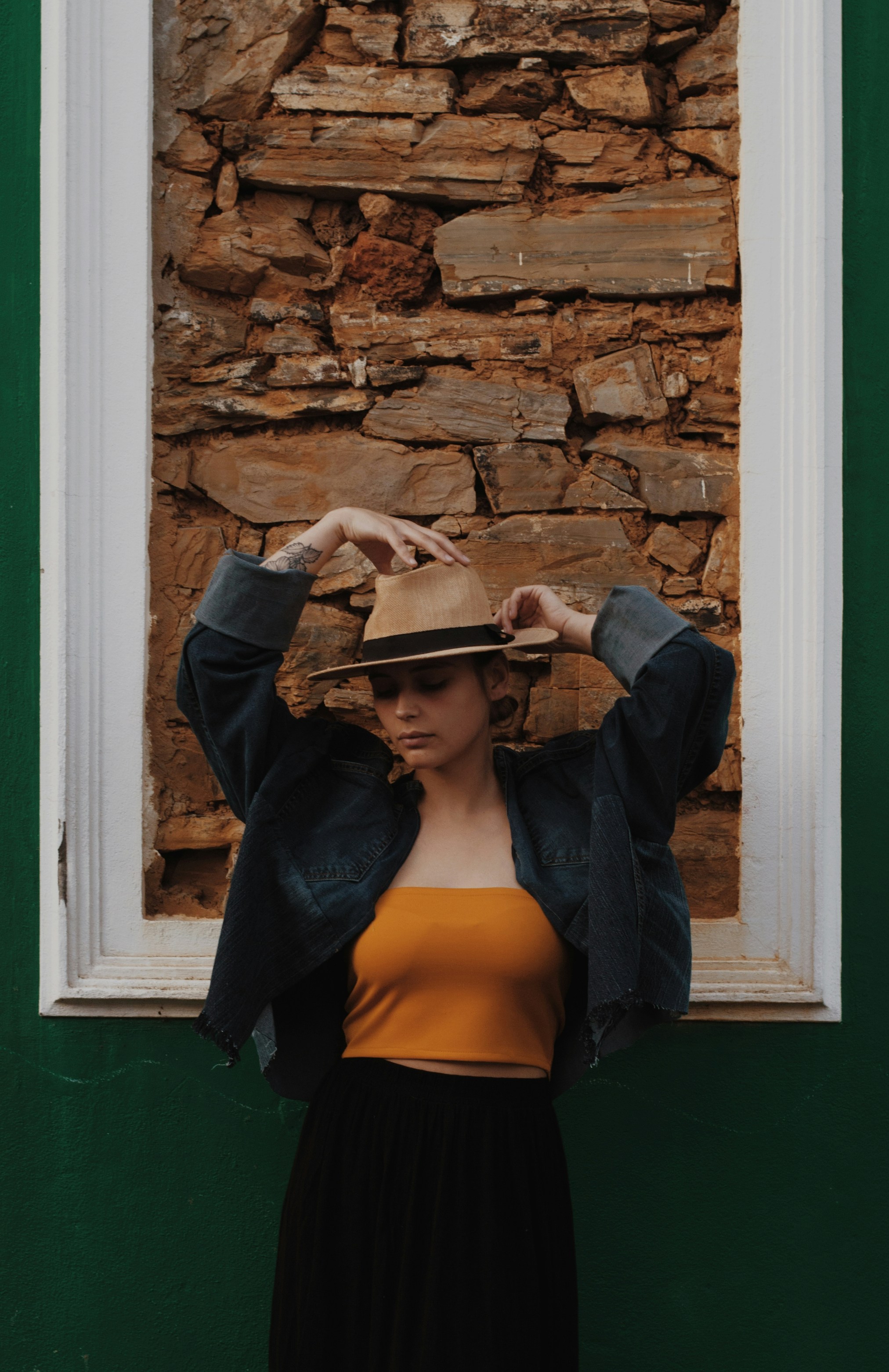 Eine Frau, die mit einem Hut auf dem Kopf vor einem Fenster steht