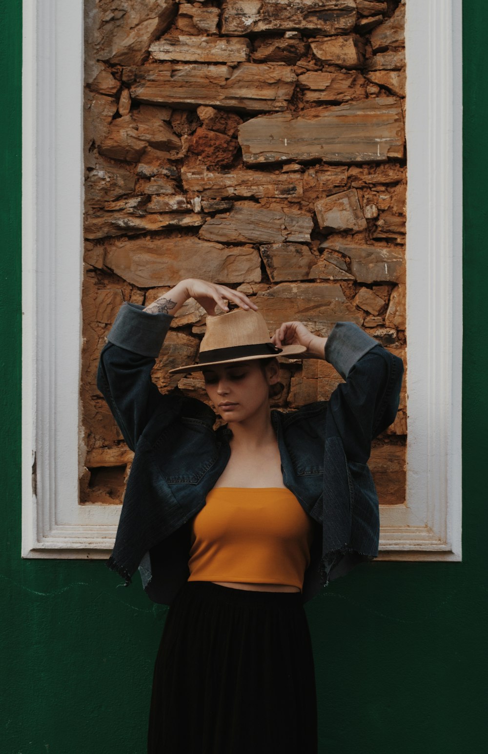 a woman standing in front of a window with a hat on her head