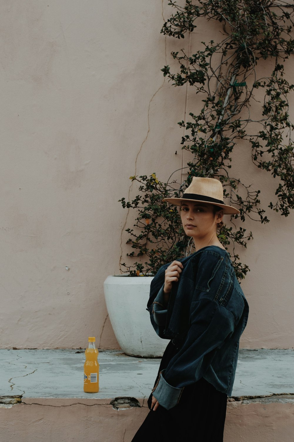 a woman standing next to a wall wearing a hat