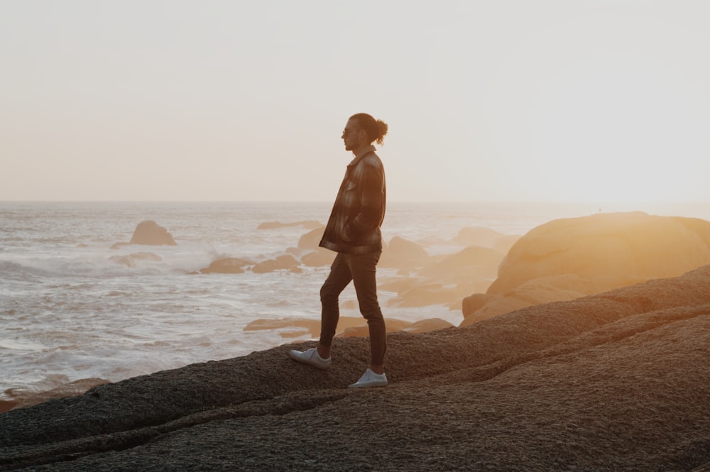 a person standing on a rock near the ocean