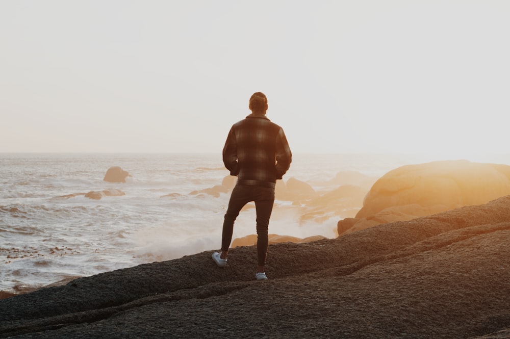 a man standing on top of a rock near the ocean