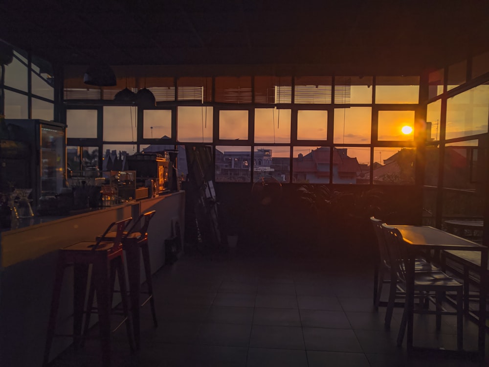 the sun is setting through the windows of a restaurant