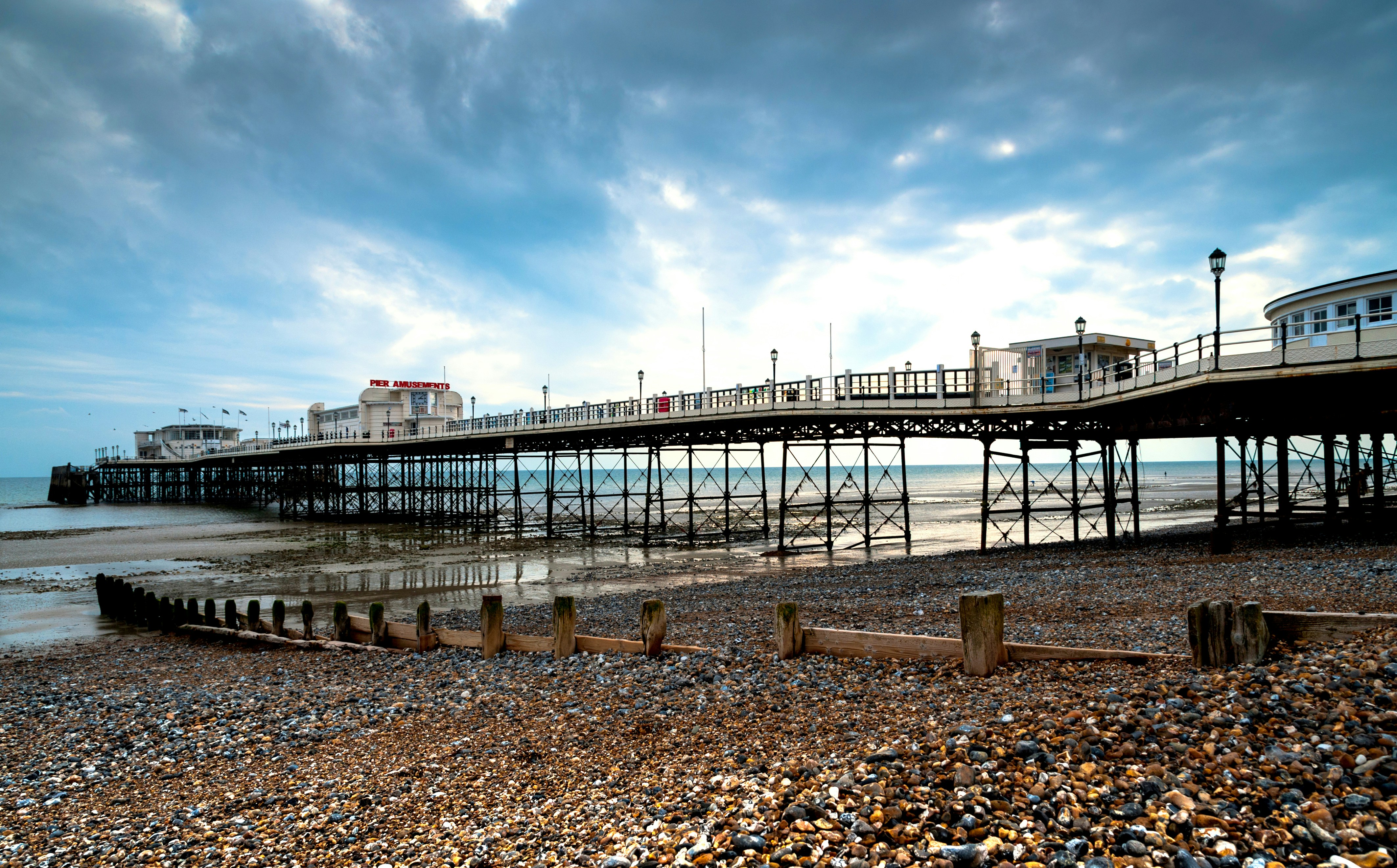 a pier on the beach with a cloudy sky