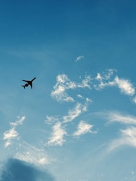 A sleek airplane taking off against a bright blue sky with soft clouds.