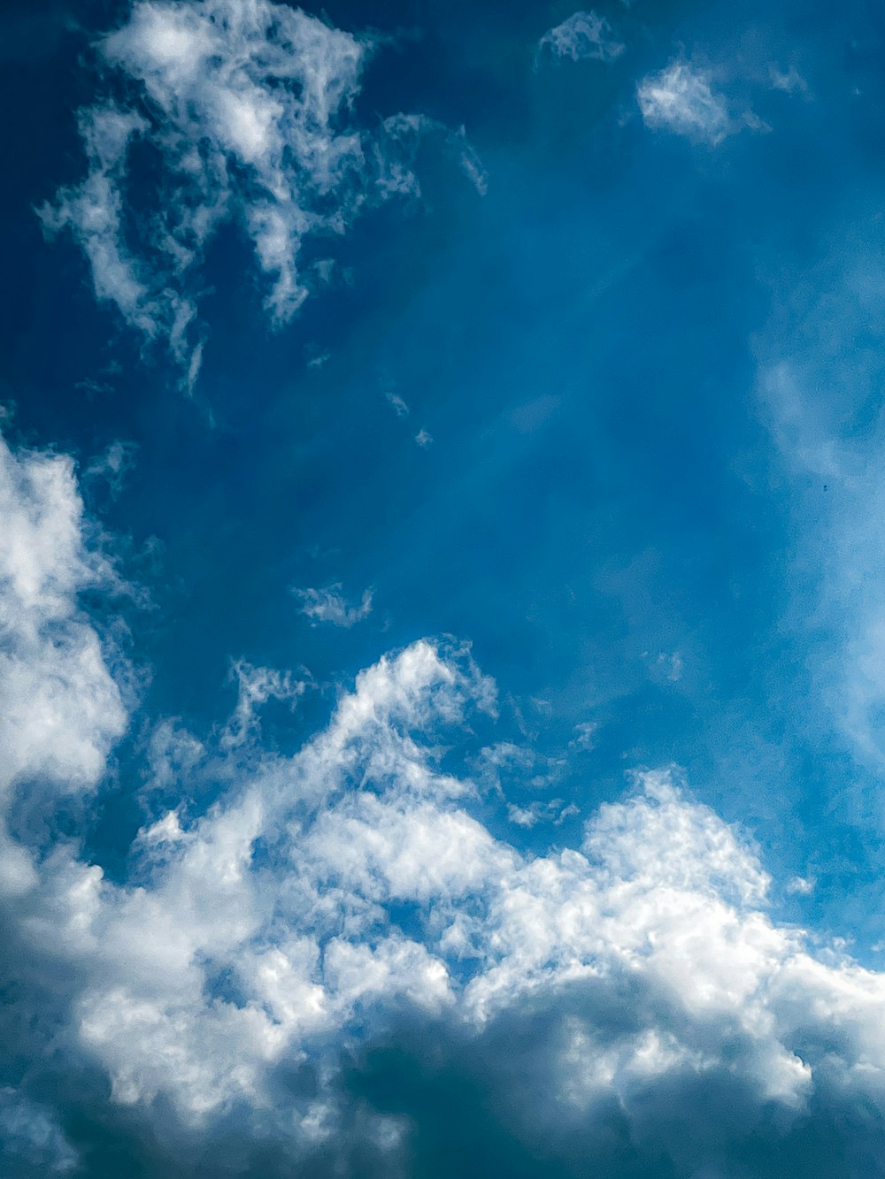 a plane flying through a cloudy blue sky