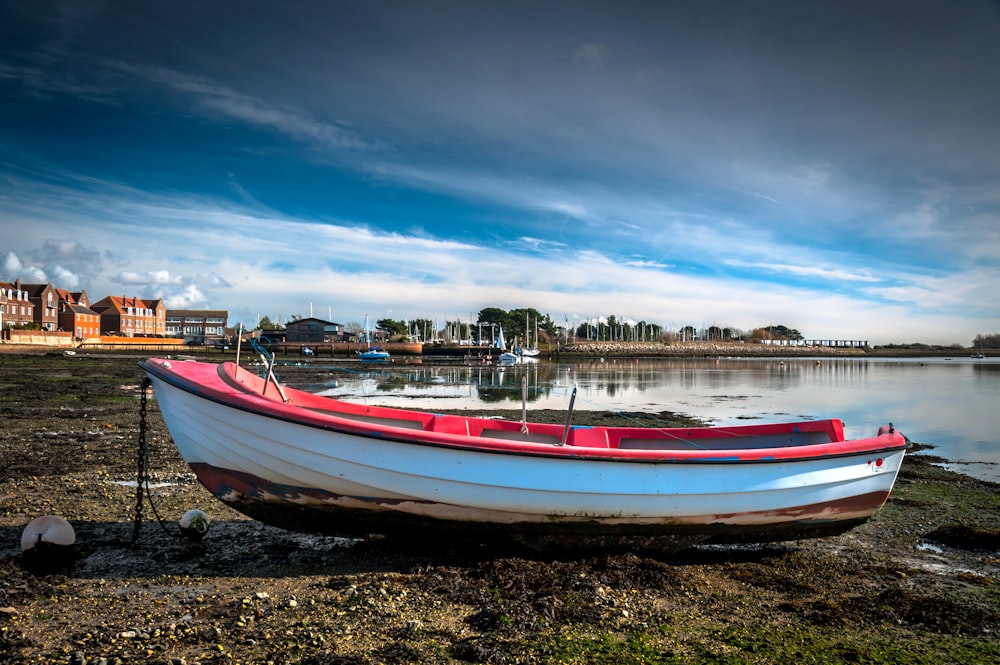 a red and white boat sitting on top of a beach