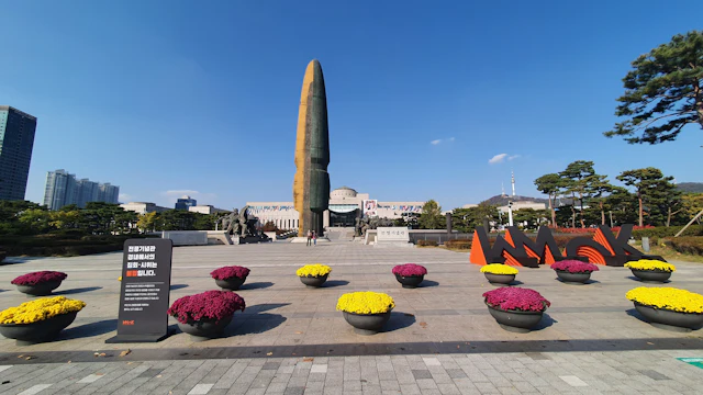 The central tower of the War Memorial of Korea in Seoul surrounded by flower displays.
