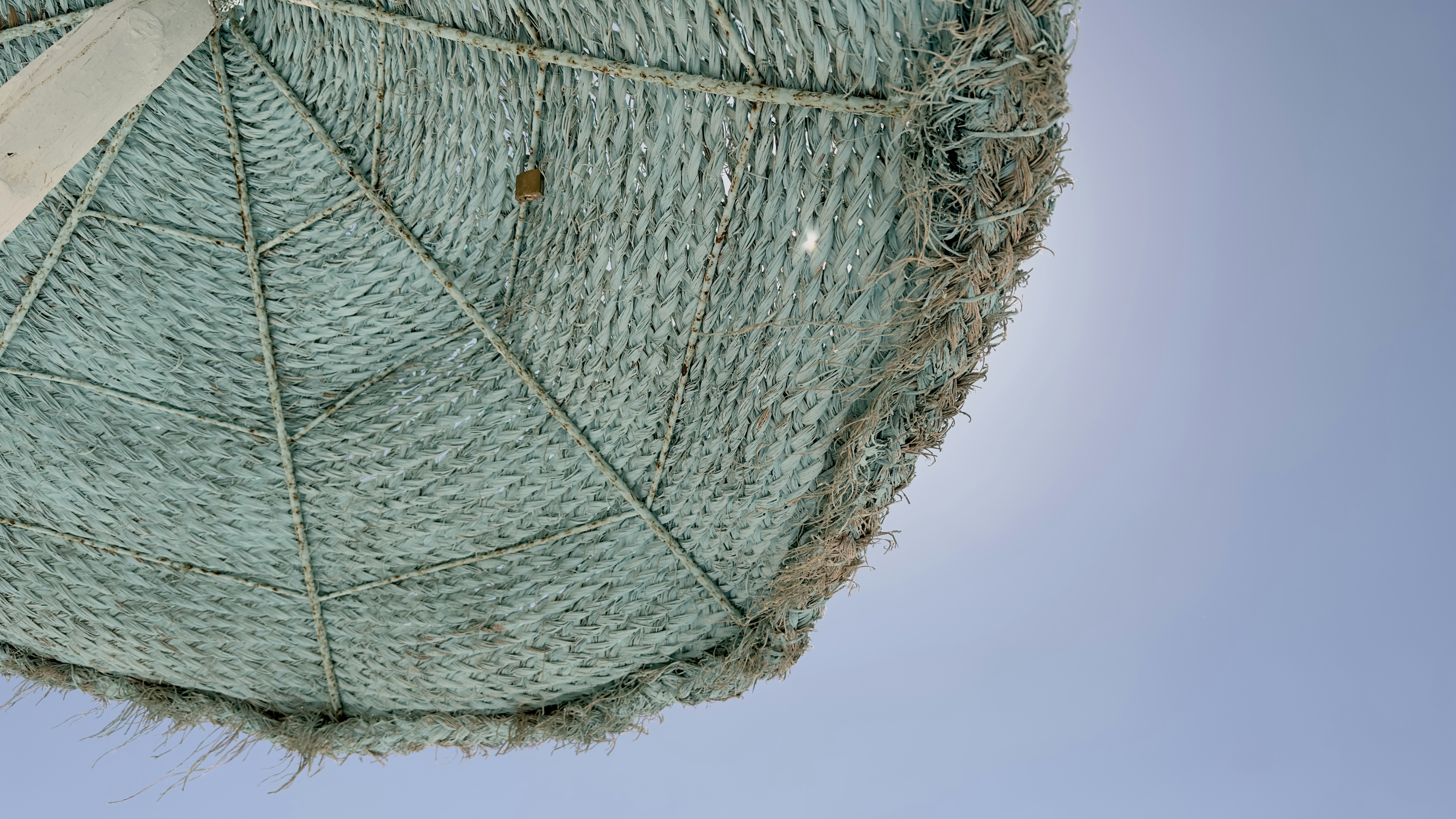 a close up of a green umbrella with a blue sky in the background