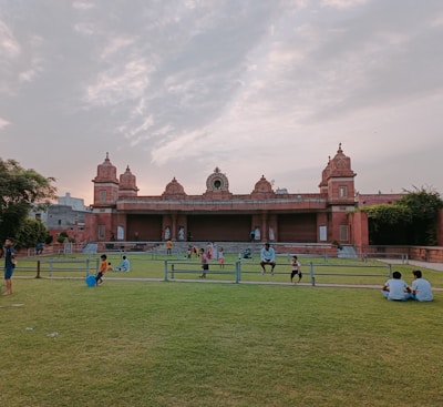 a group of people sitting on top of a lush green field