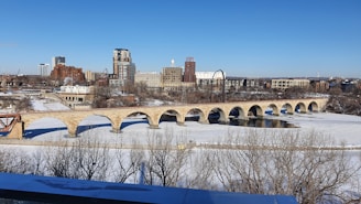a bridge over a frozen river with a city in the background