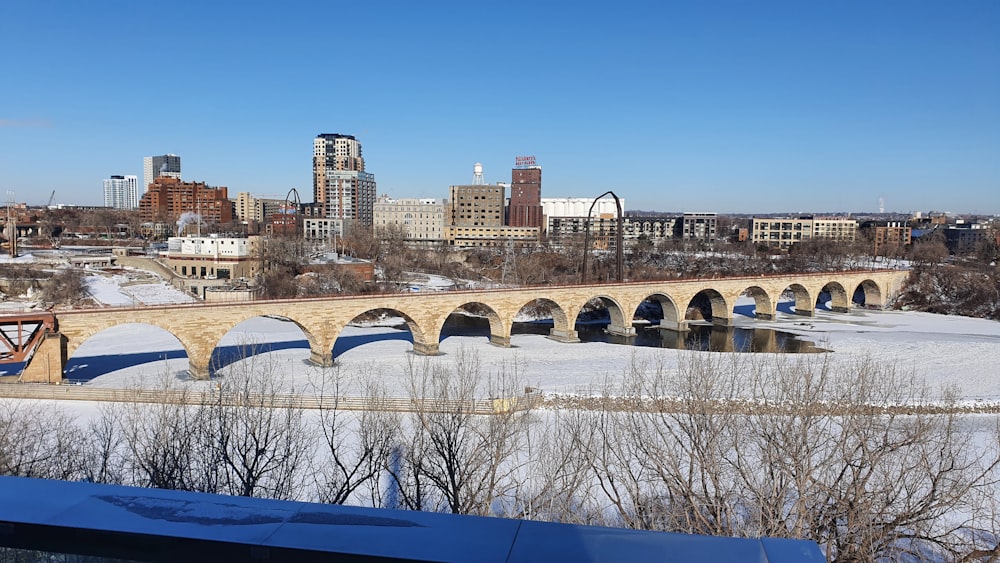 a bridge over a frozen river with a city in the background