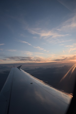 A scenic flight window view showing clouds and a sunset horizon.