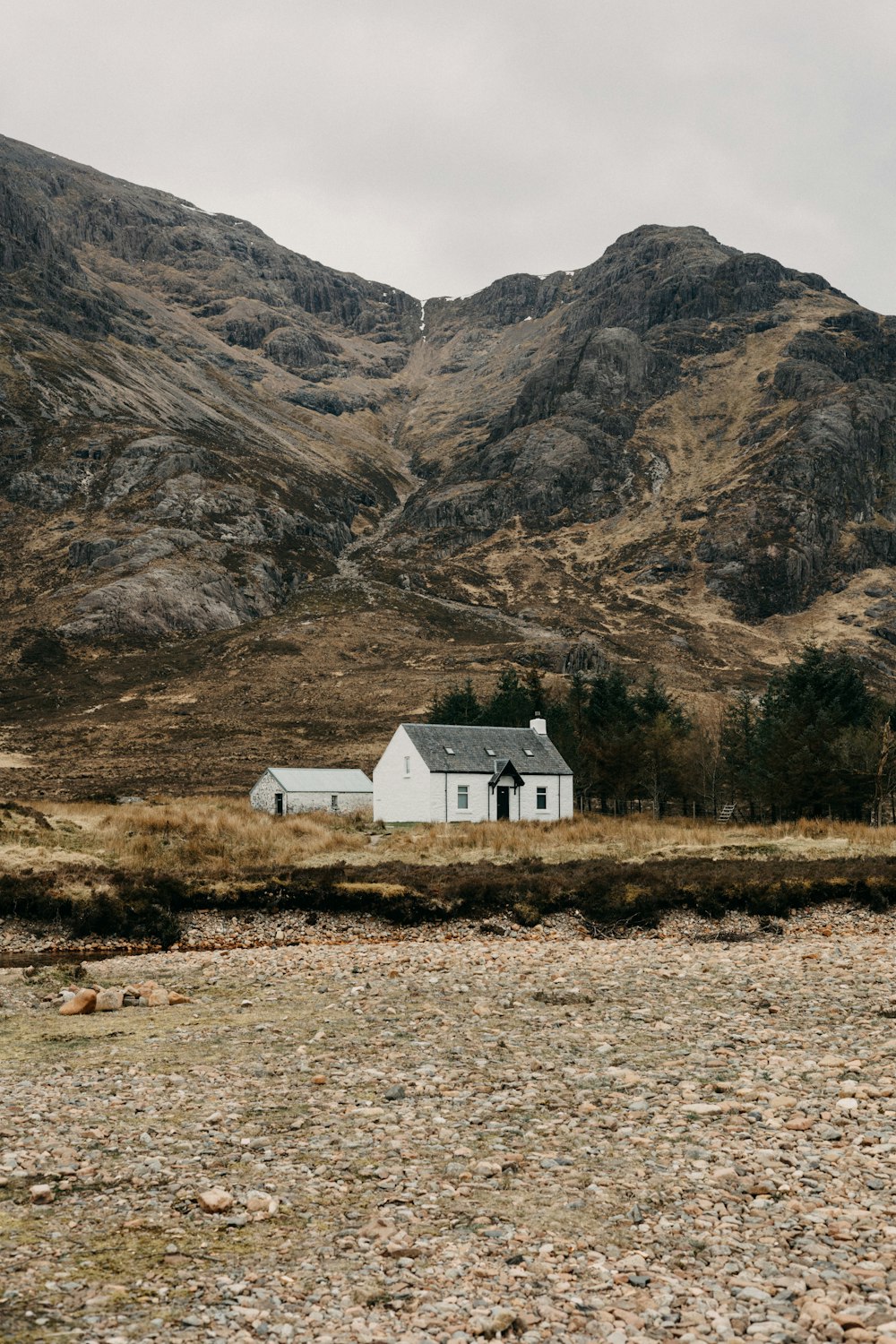 a house in the middle of a field with mountains in the background