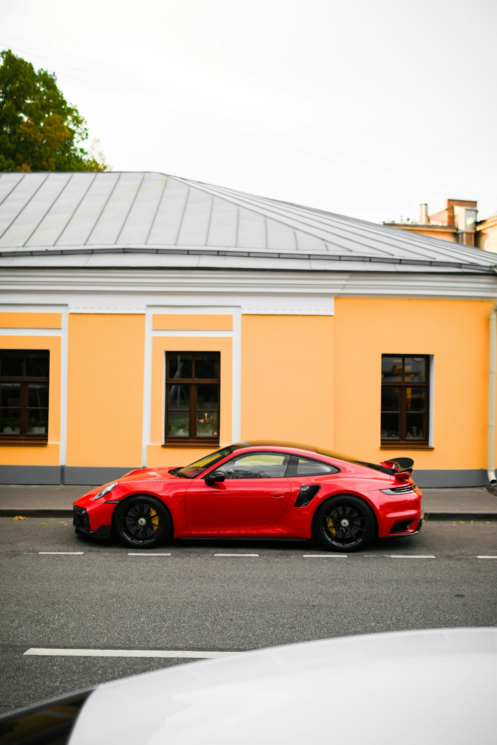 a red sports car parked in front of a yellow building