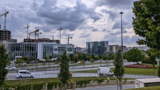 A panoramic view of a modern urban development project under construction with cranes and glass façades.