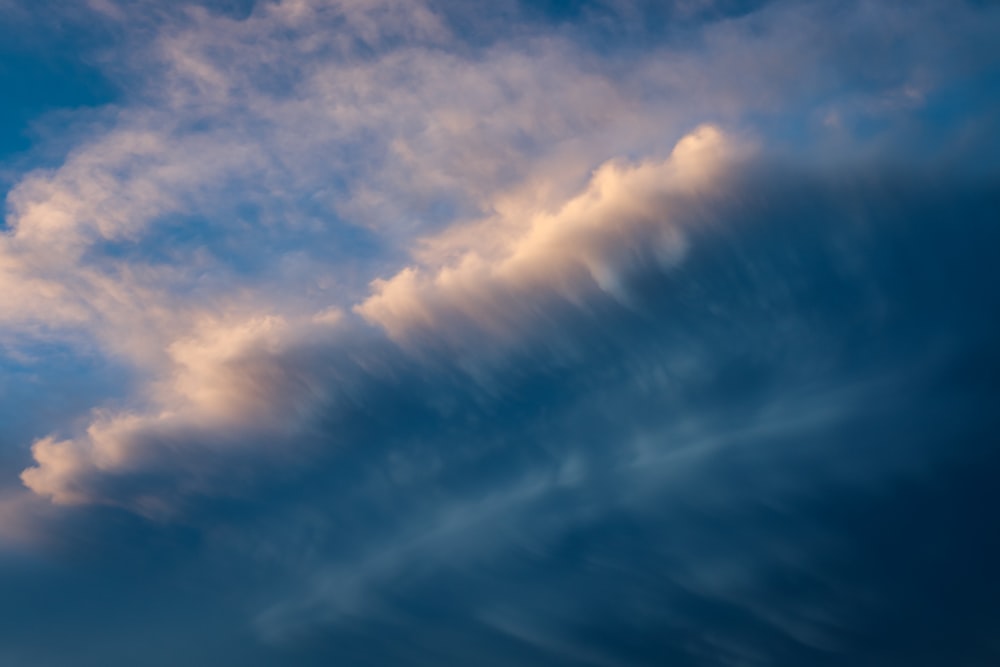 a plane flying through a cloudy blue sky