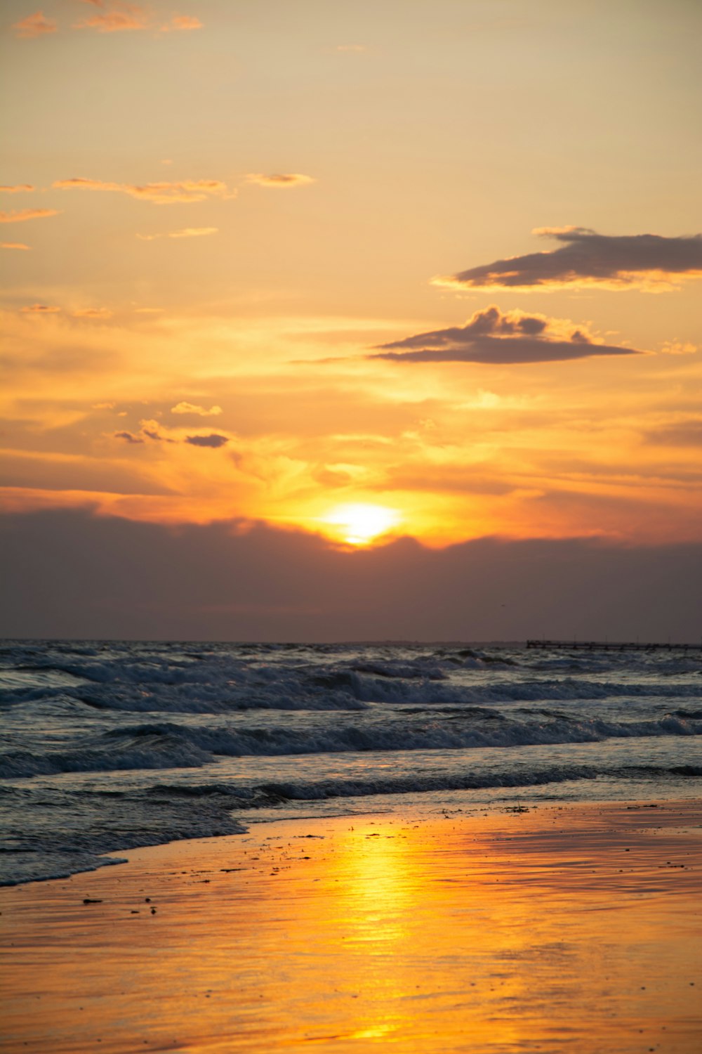 the sun is setting over the ocean on the beach