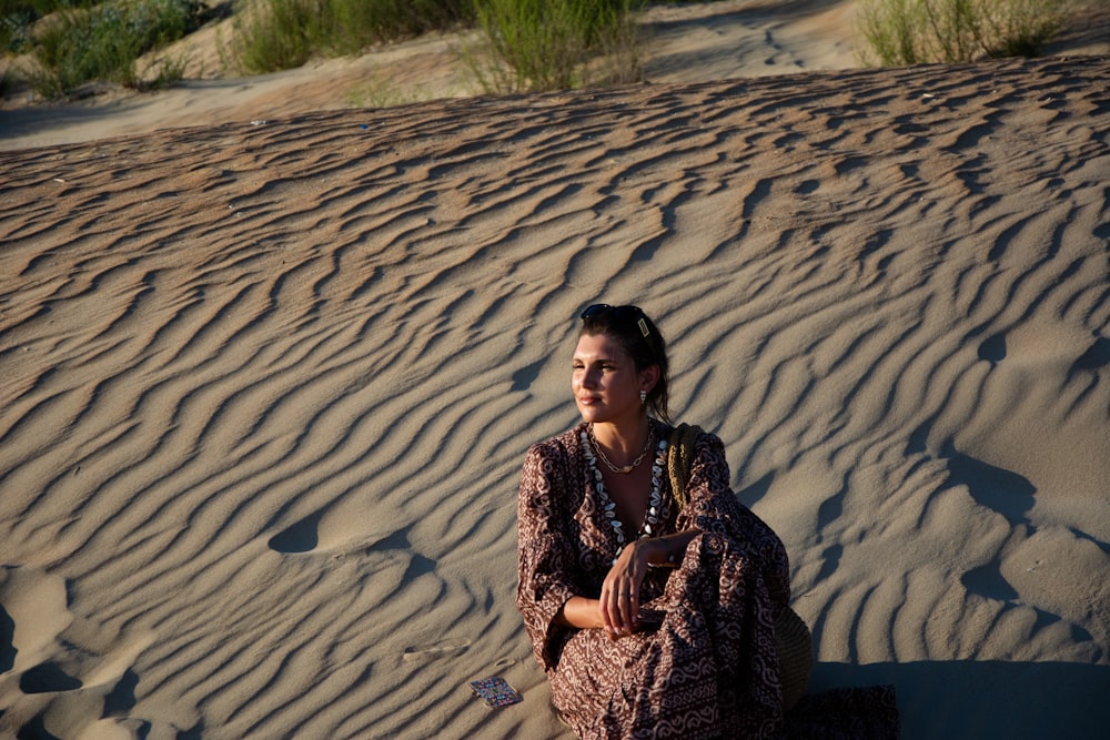 a woman sitting on top of a sandy beach