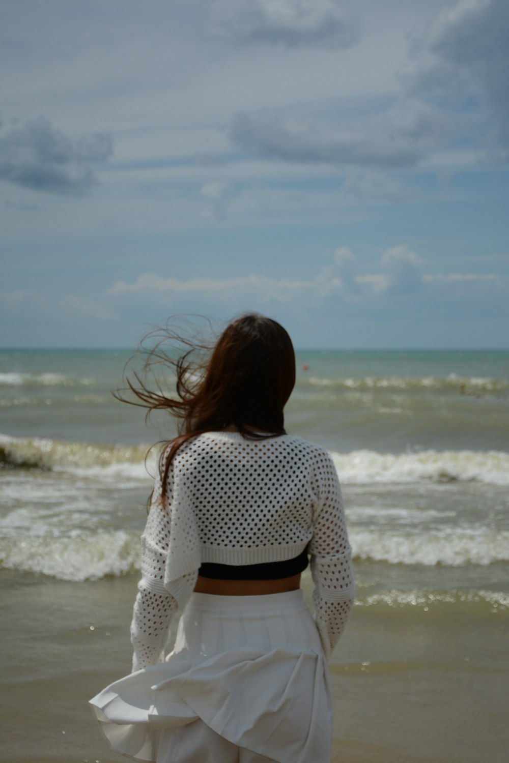 a woman walking along a beach next to the ocean