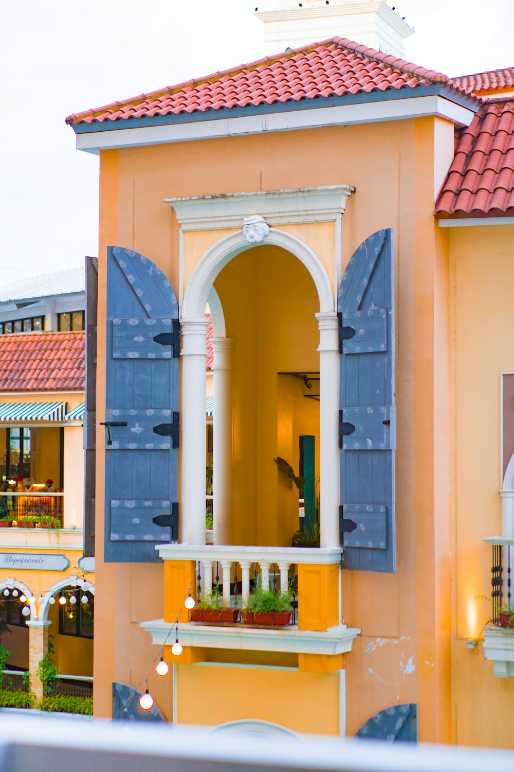 a yellow building with blue shutters and a red roof