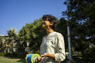 A child smiling while holding a colorful paper kite in a park.