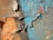 Chipped and peeling paint on a rough, textured surface with layers of rusty orange, blue, and bits of red color.