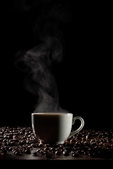 A steaming cup of coffee is enveloped by rising vapor against a dark background. The cup is surrounded by scattered coffee beans on a wooden surface, casting subtle shadows. The atmosphere conveys a sense of warmth and coziness.