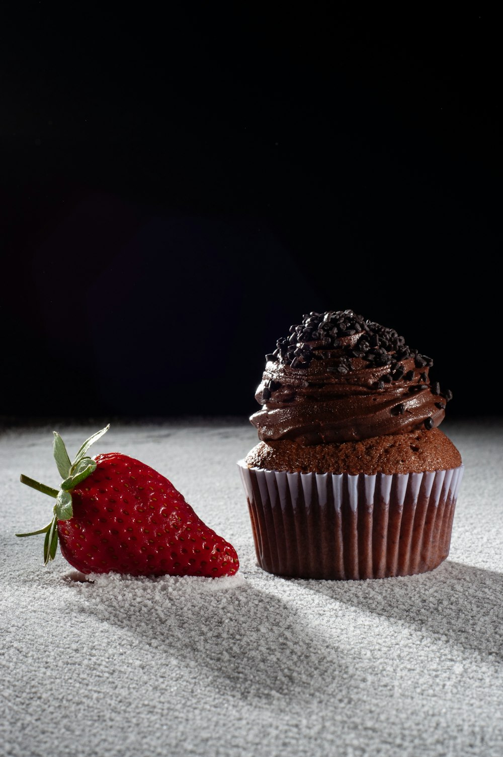 a chocolate cupcake with a strawberry on the side