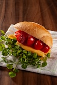 a hot dog with ketchup, cheese, and tomatoes