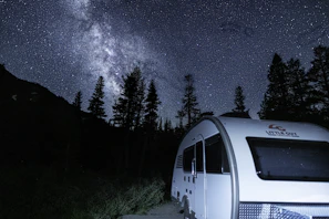 Night sky filled with stars above the minimotorhome parked in a quiet forest clearing