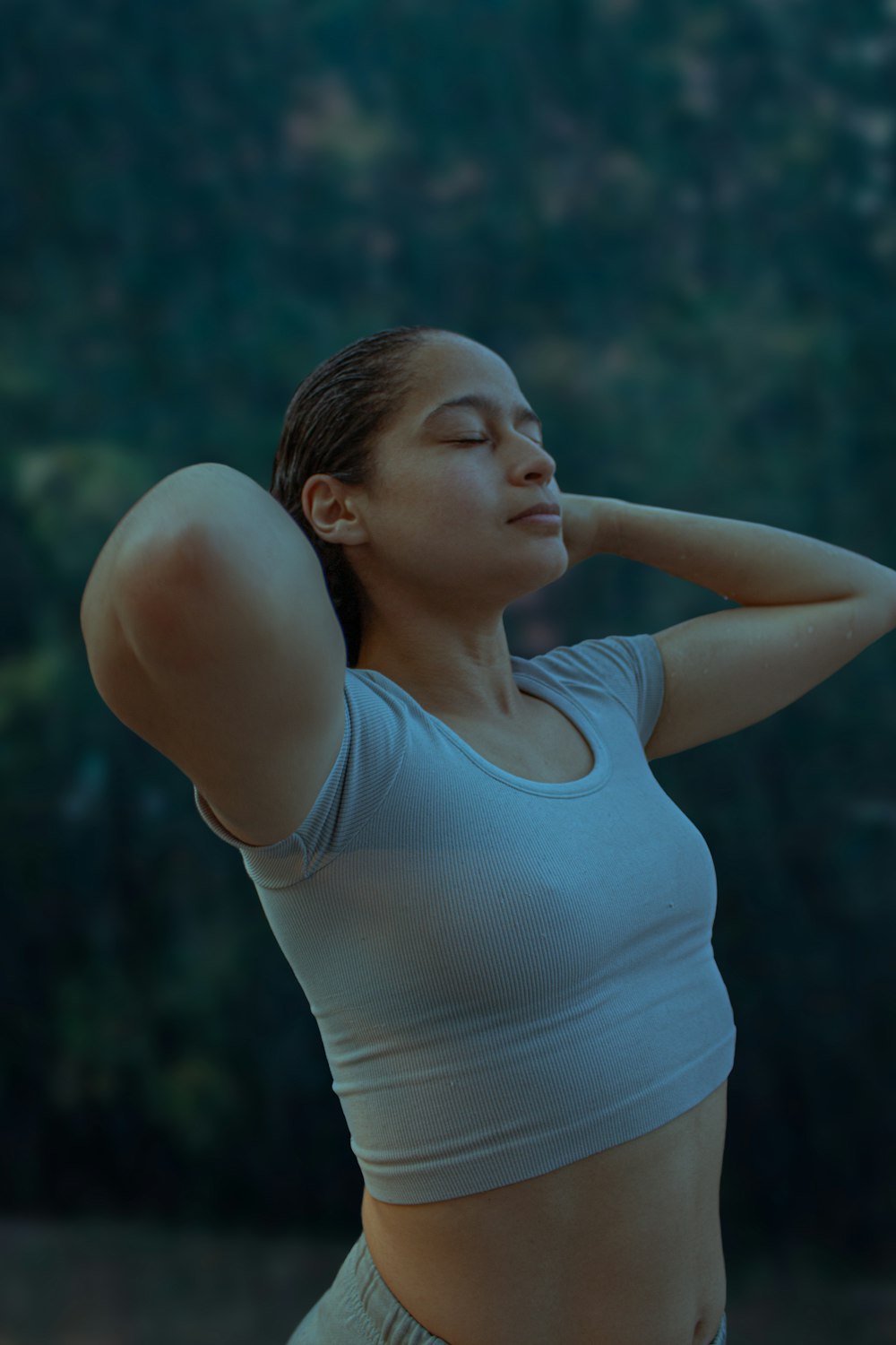 a woman stretching her arms with her hands behind her head